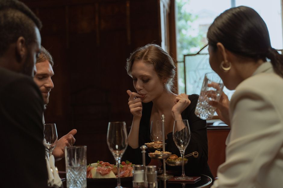People dining at restaurant table with drinks and food, enjoying meal experience